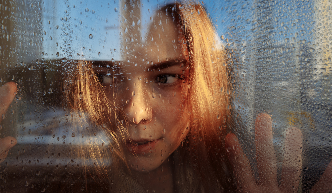 A woman turning away from a rainy window