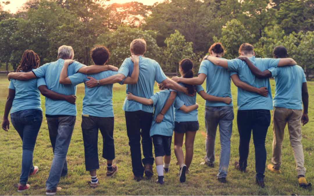 A group of people in matching shirts walking across a field with their arms around each other