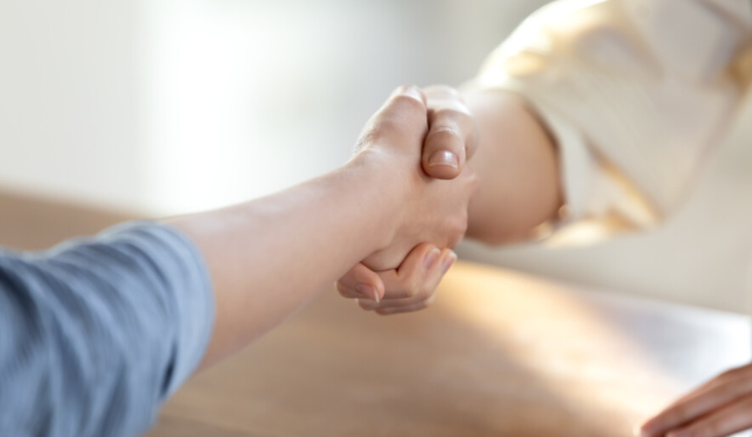 Two people shaking hands across a table