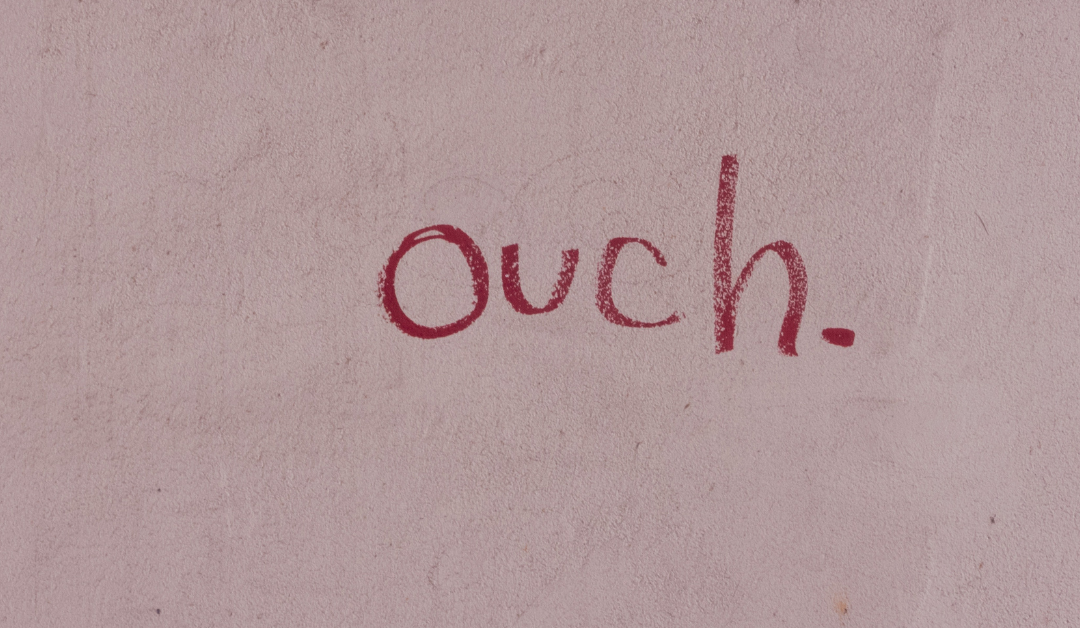 Graffiti on a wall that reads "Ouch."